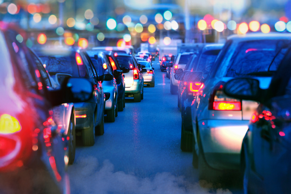 Nighttime traffic with stationary cars emitting pollution into the environment.